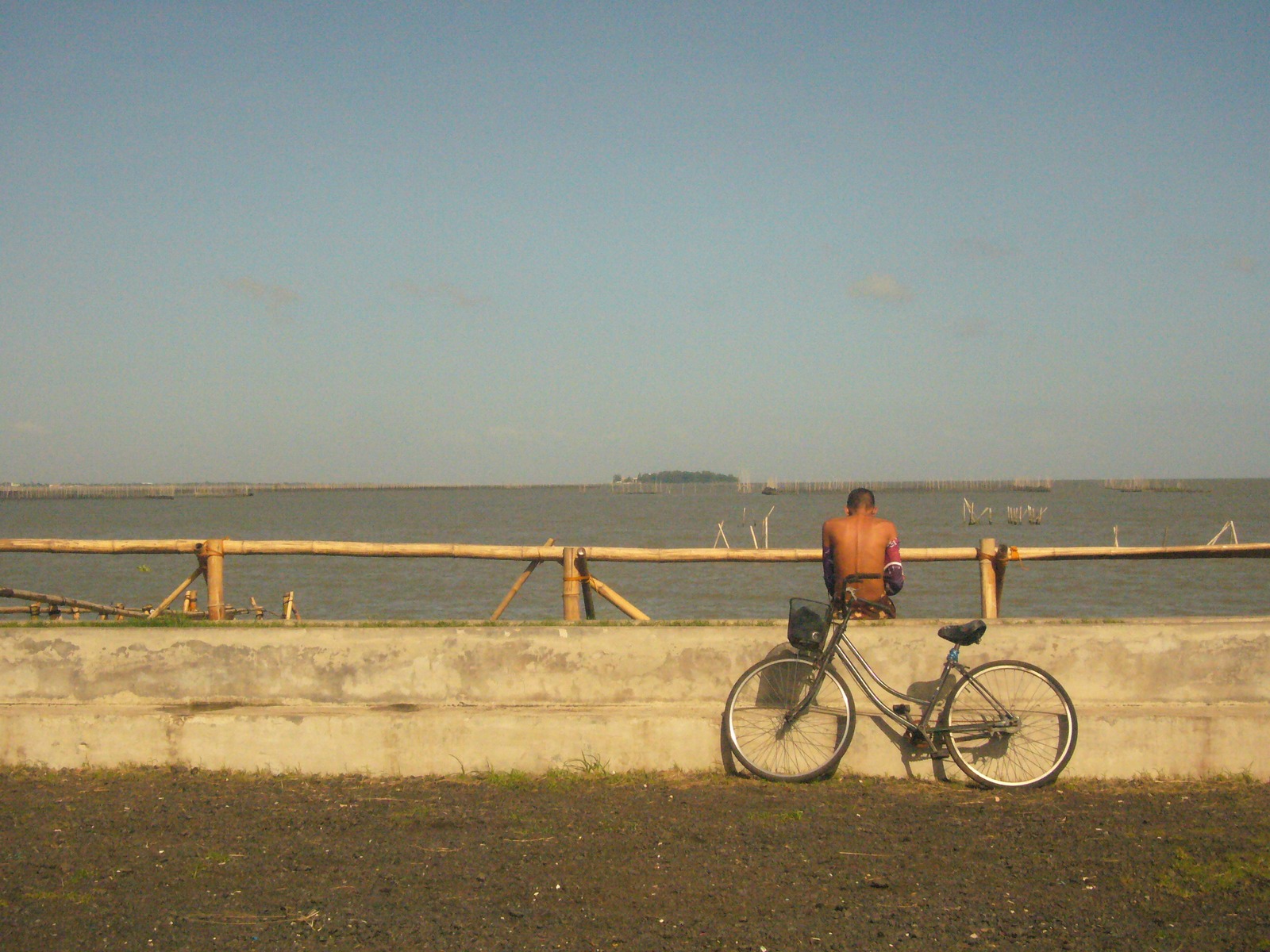 A man, sitting and facing the lake